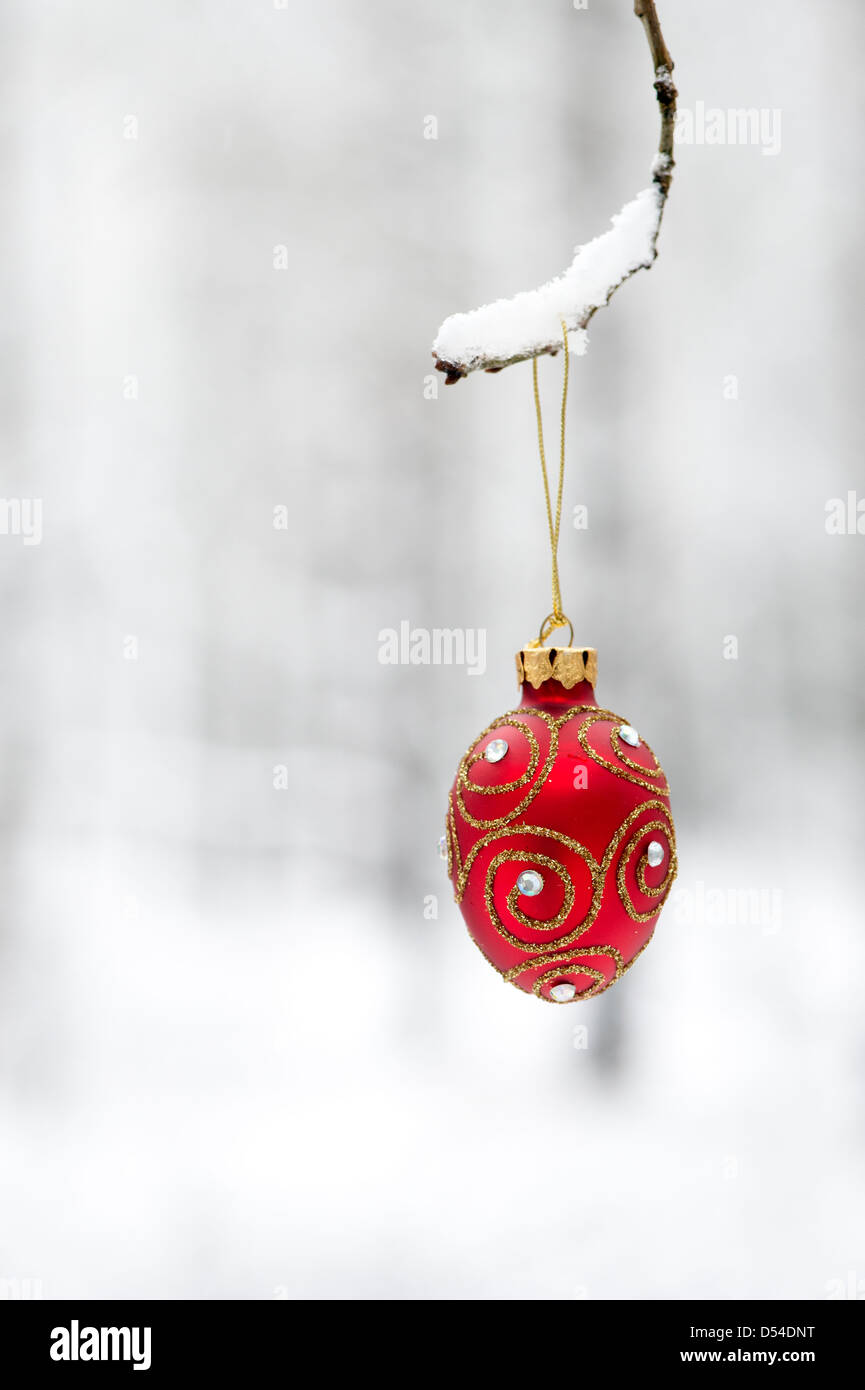 Christmas tree decorations / baubles hanging on a tree branch in the snow Stock Photo