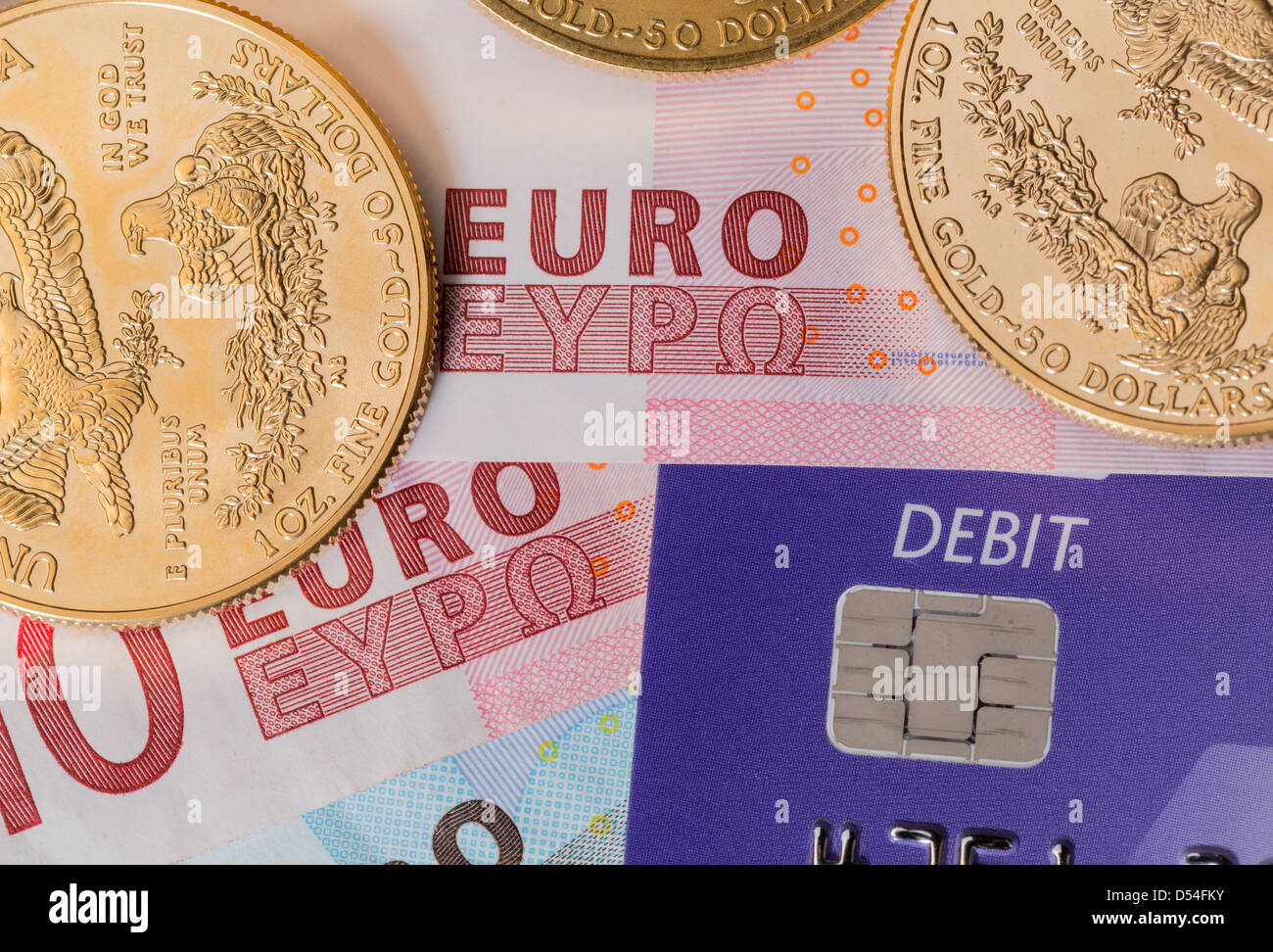Solid gold coins contrasted with debit word on plastic card on euro note suggesting debt problems Stock Photo