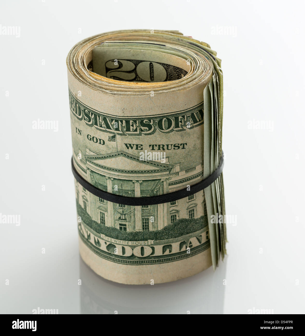 Roll of many $20 dollar bills and notes secured by elastic band on white table Stock Photo