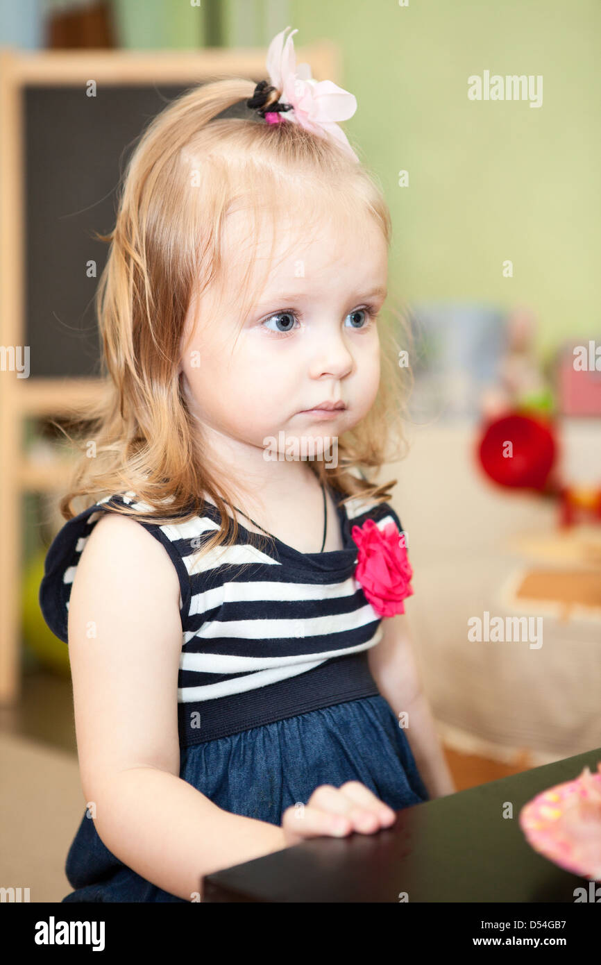 Cute young child sitting at the table in domestic room Stock Photo Alamy
