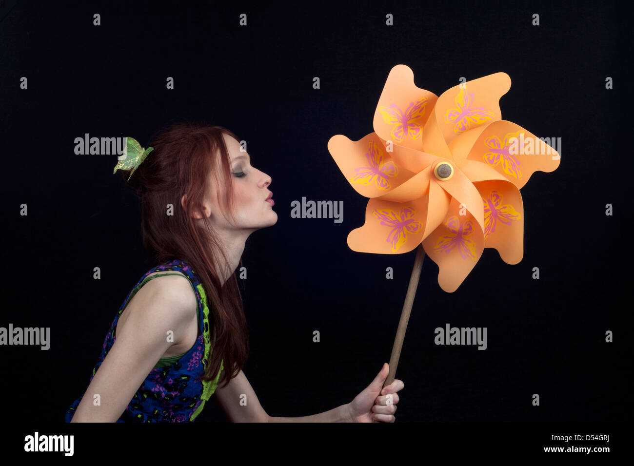 Girl with an orange pinwheel against black background Stock Photo