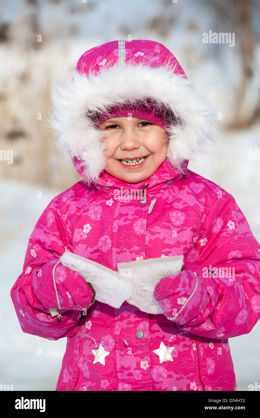 Happy laughing child in winter clothes with piece of ice in hands Stock Photo