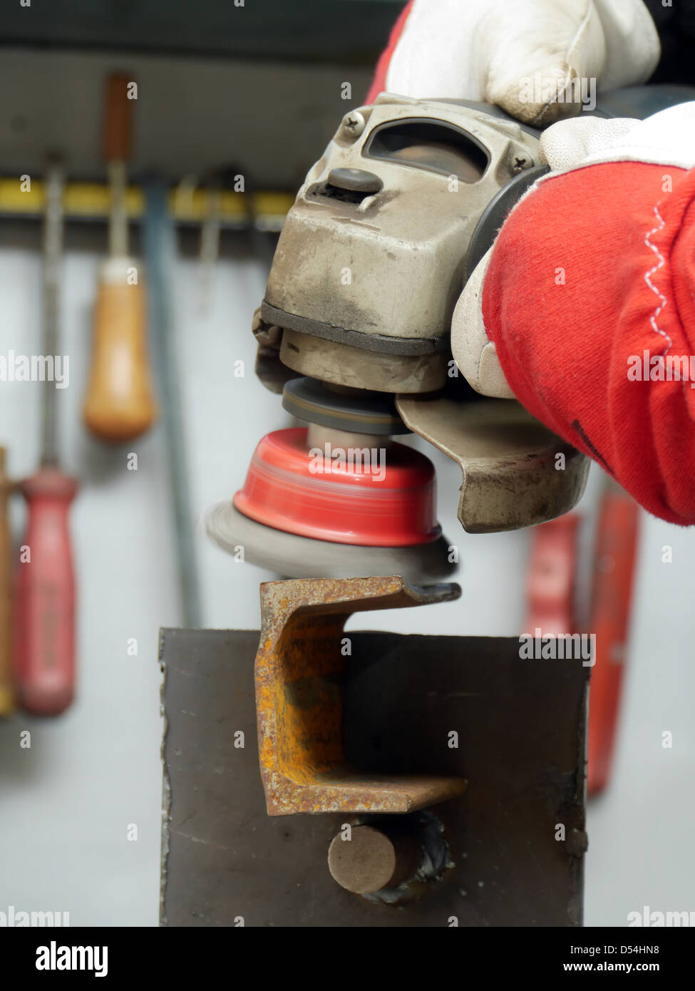 Closeup of machinist worker hands brushing a metal piece using wire brush on angle grinder Stock Photo