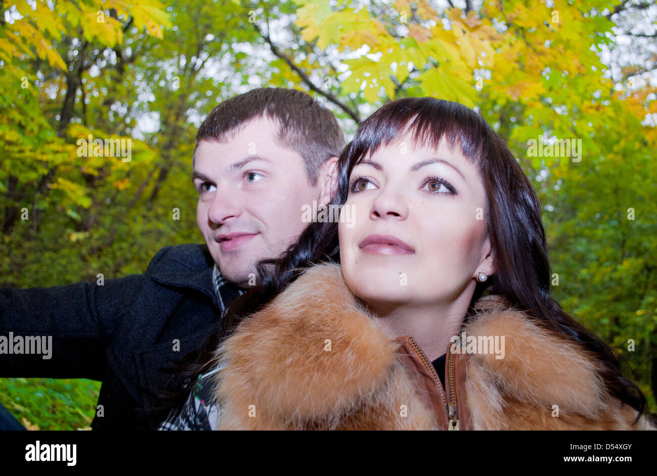 lover pair are siting in the autumn cold forest in embrace and are looking up Stock Photo