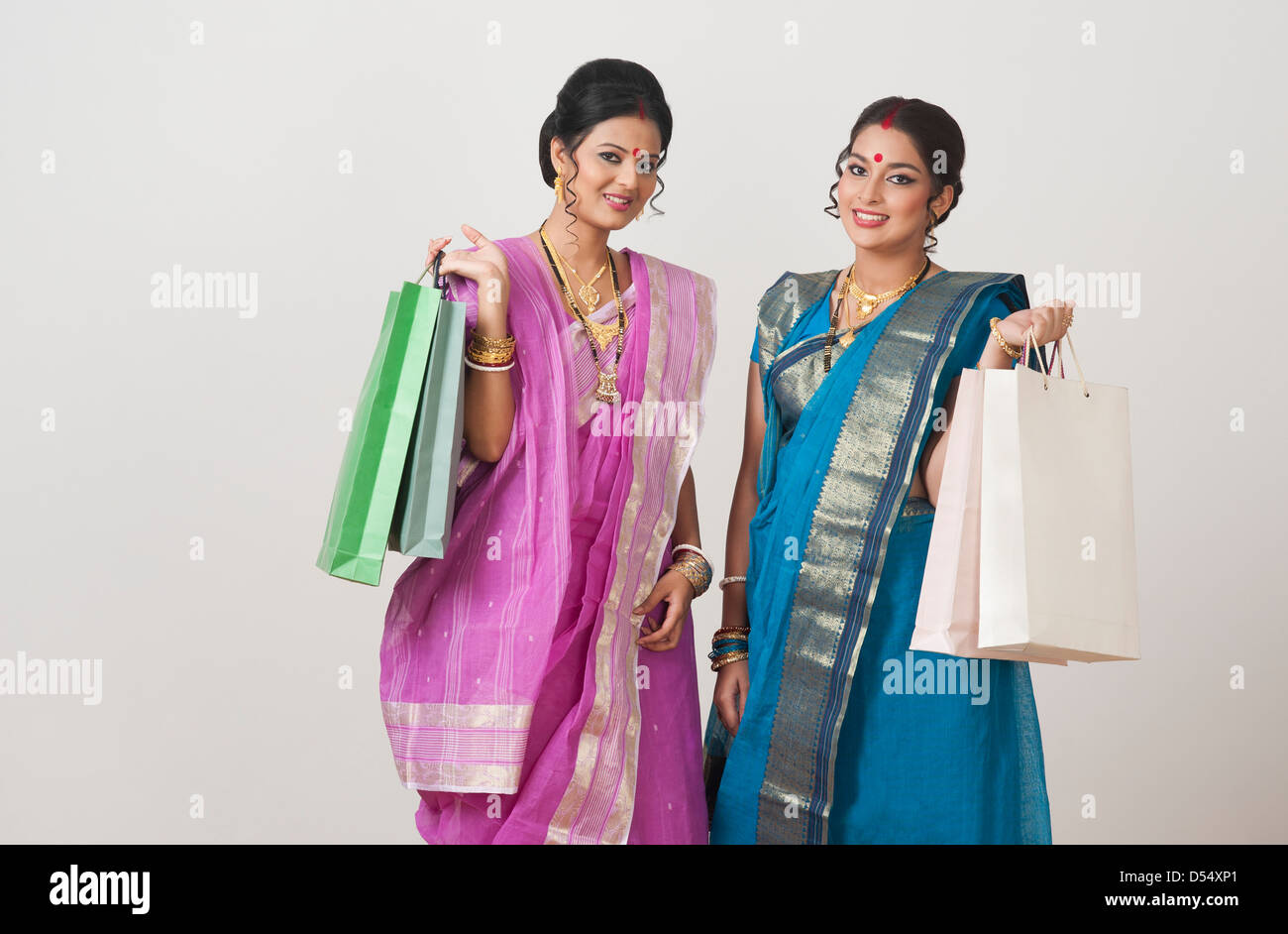 Portrait of two Bengali women carrying shopping bags and smiling Stock