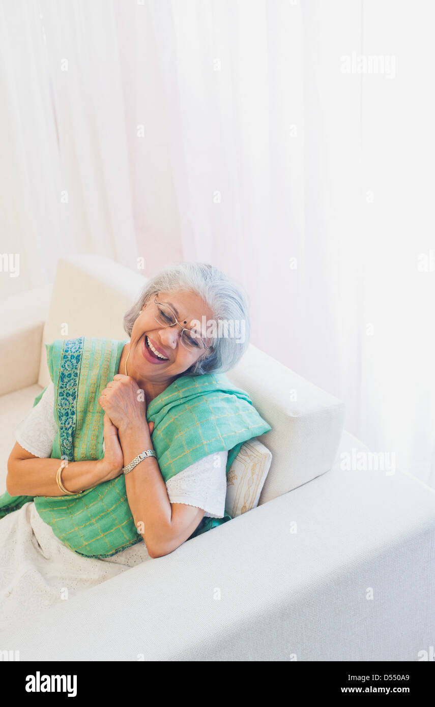 Senior woman sitting on a sofa and smiling Stock Photo - Alamy