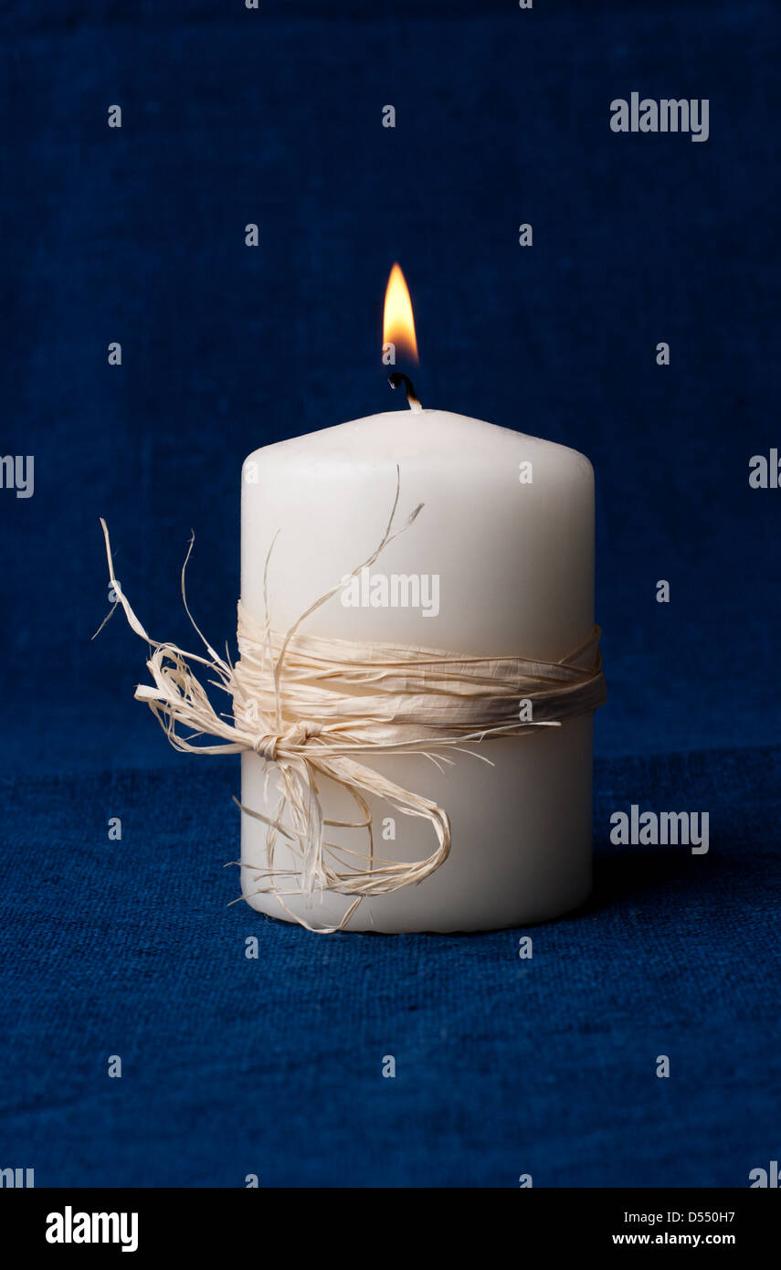 White candle that is lit on a dark blue background Stock Photo Alamy