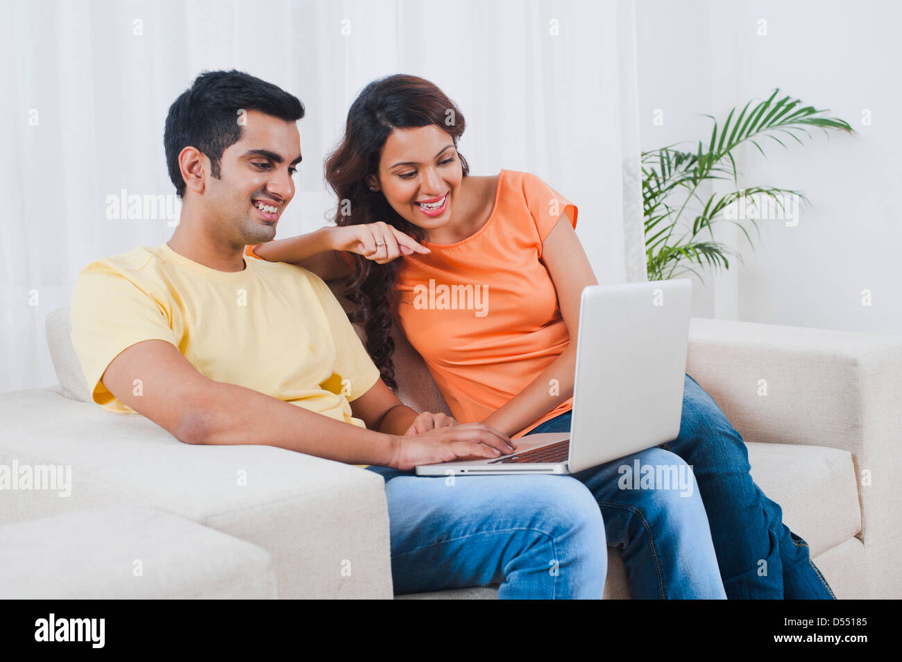 Couple using a laptop on a couch Stock Photo - Alamy