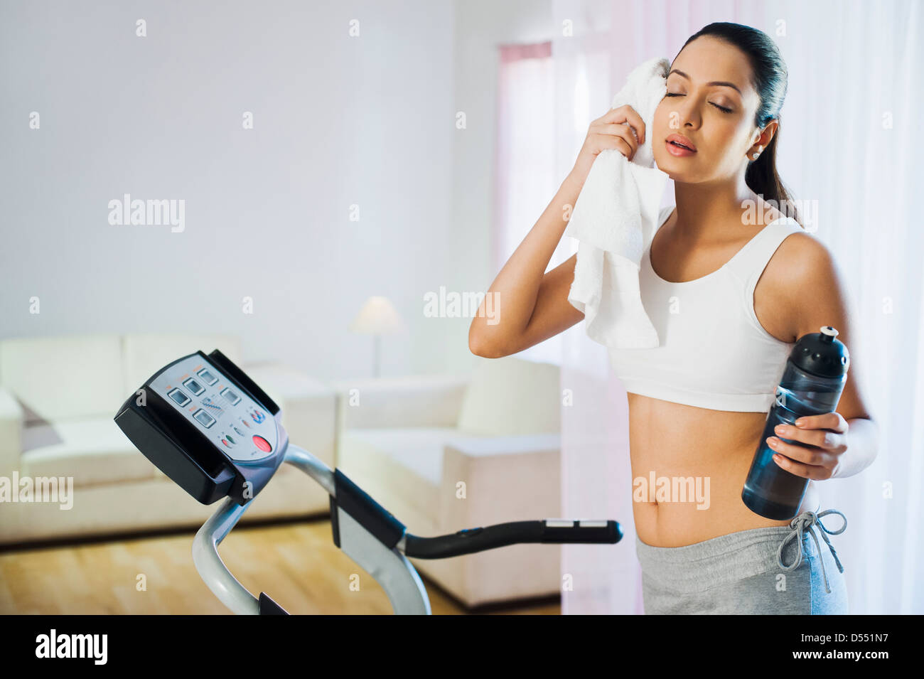 Woman standing on a treadmill and wiping her sweat Stock Photo Alamy