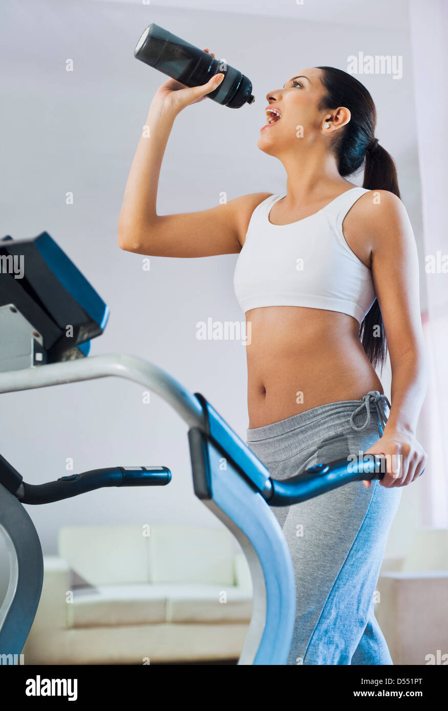 Woman running on a treadmill and drinking water Stock Photo Alamy