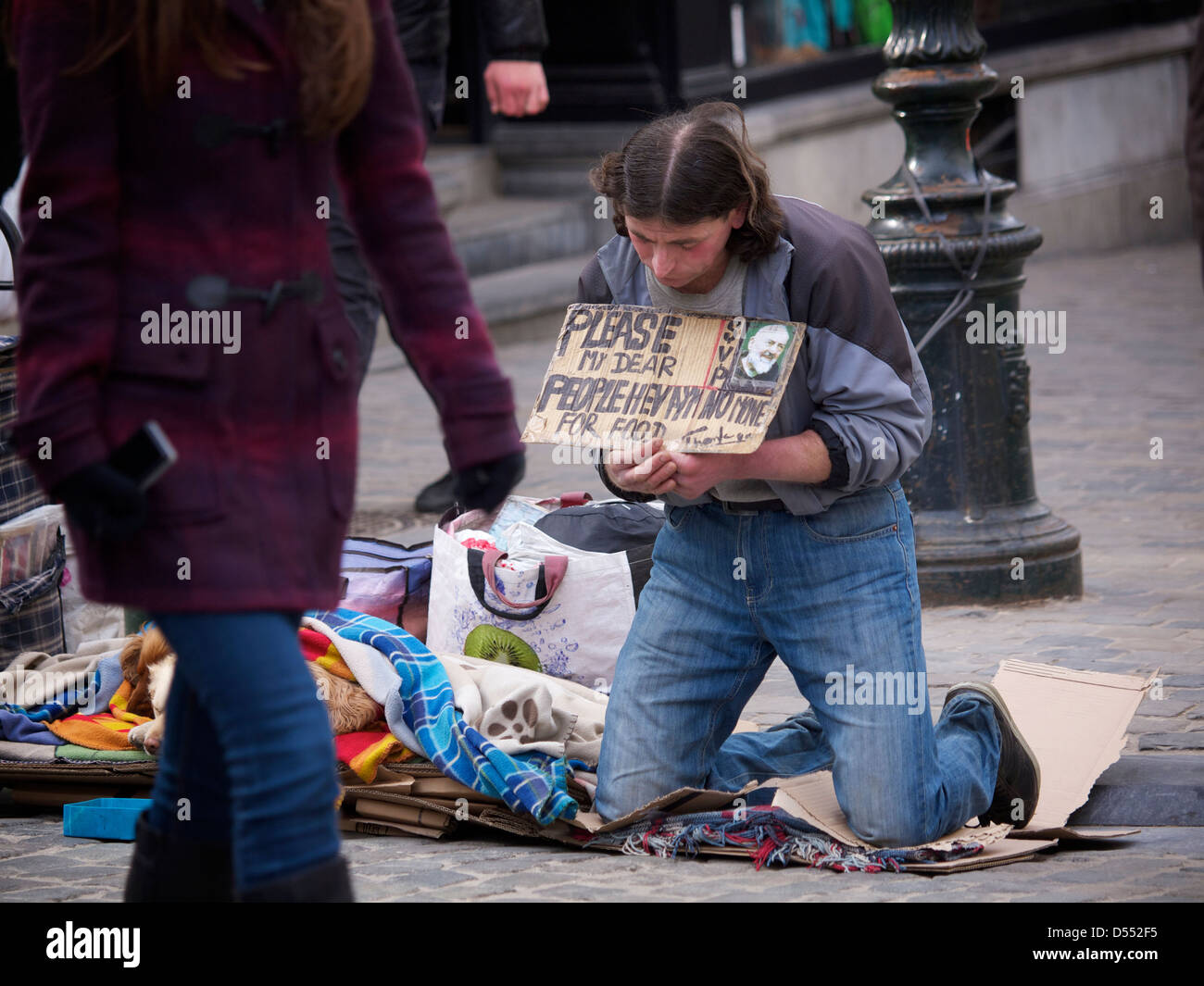 Homeless man begging for money using a sign, in the city centre of Brussels, Belgium Stock Photo