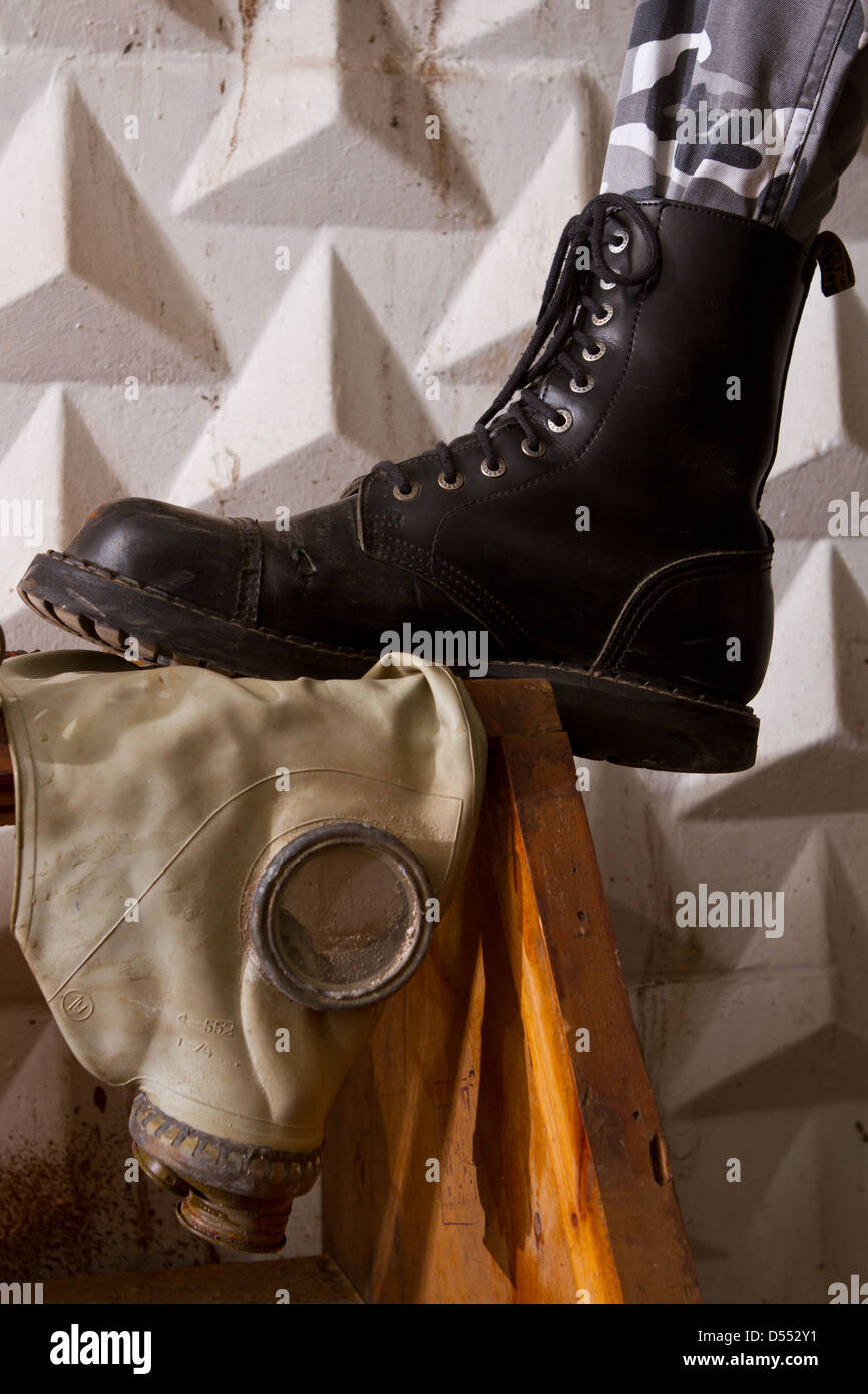 black army boots standing on gas mask in an abandoned basement Stock Photo