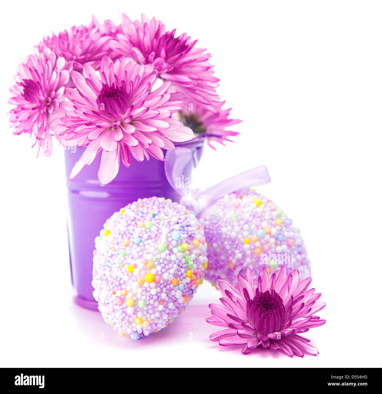 Beautiful Easter still life isolated on white background, decorated chicken eggs, fresh pink flowers in purple bucket Stock Photo