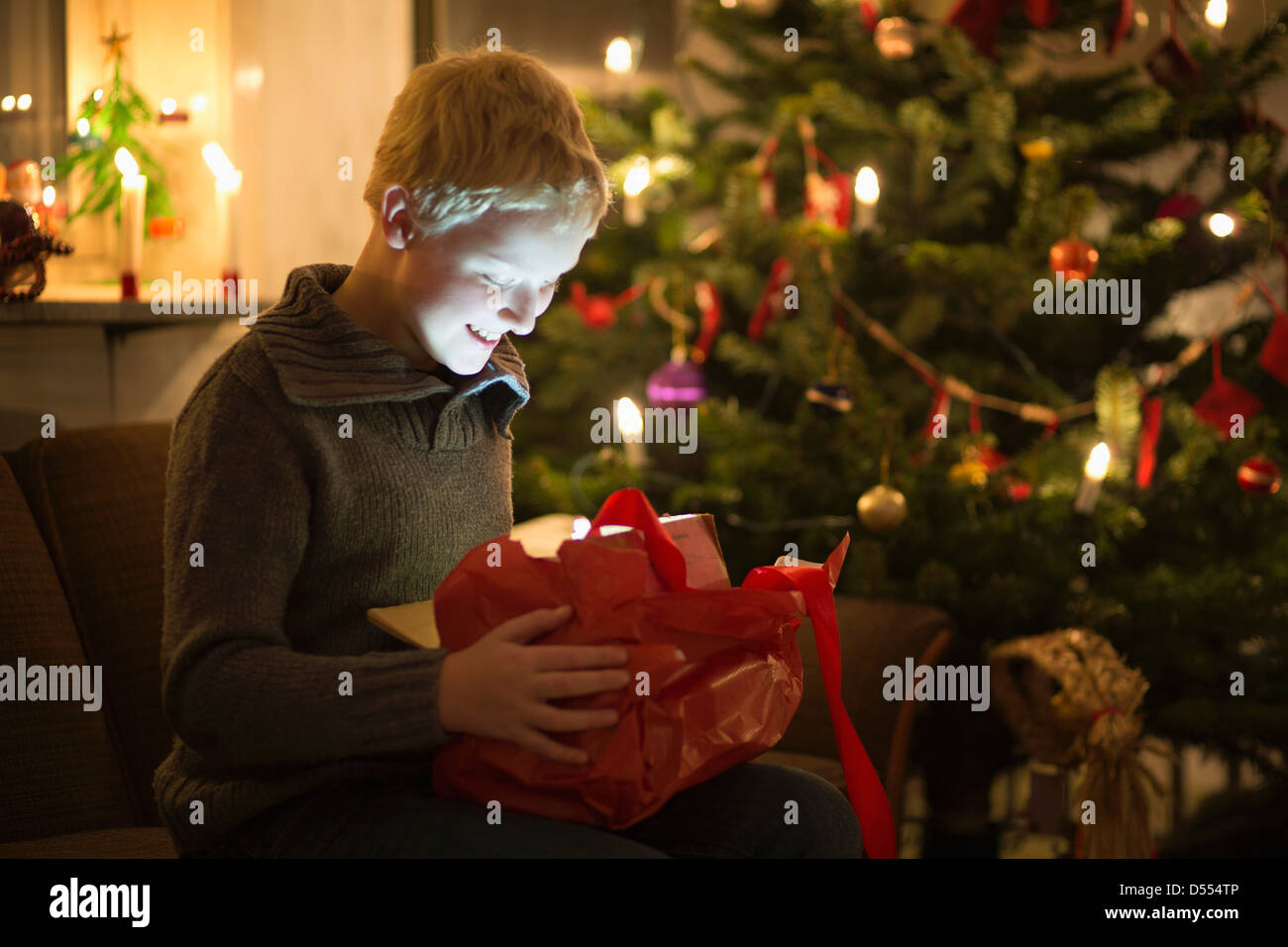 Smiling boy opening Christmas present Stock Photo Alamy