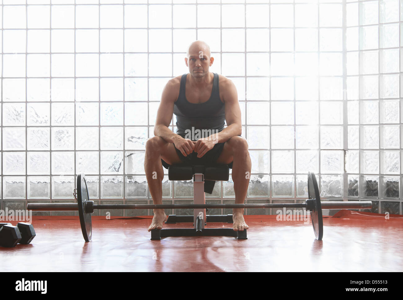 Man sitting with weights in gym Stock Photo