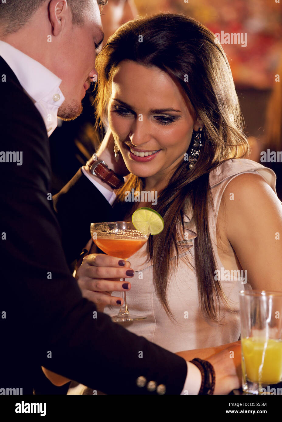Woman listening as her boyfriend whispers something romantic to her Stock Photo