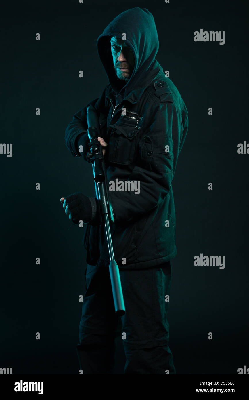 Sniper with beard in black holding gun. Studio shot. Stock Photo