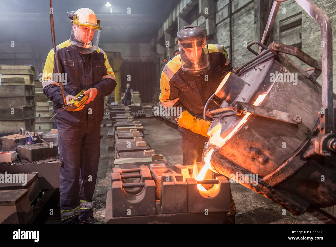 Workers pouring molten metal in foundry Stock Photo