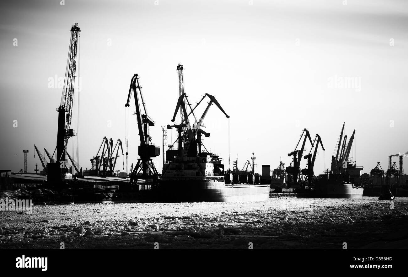 Silhouette of cargo port skyline with cranes, ships and poles Stock Photo