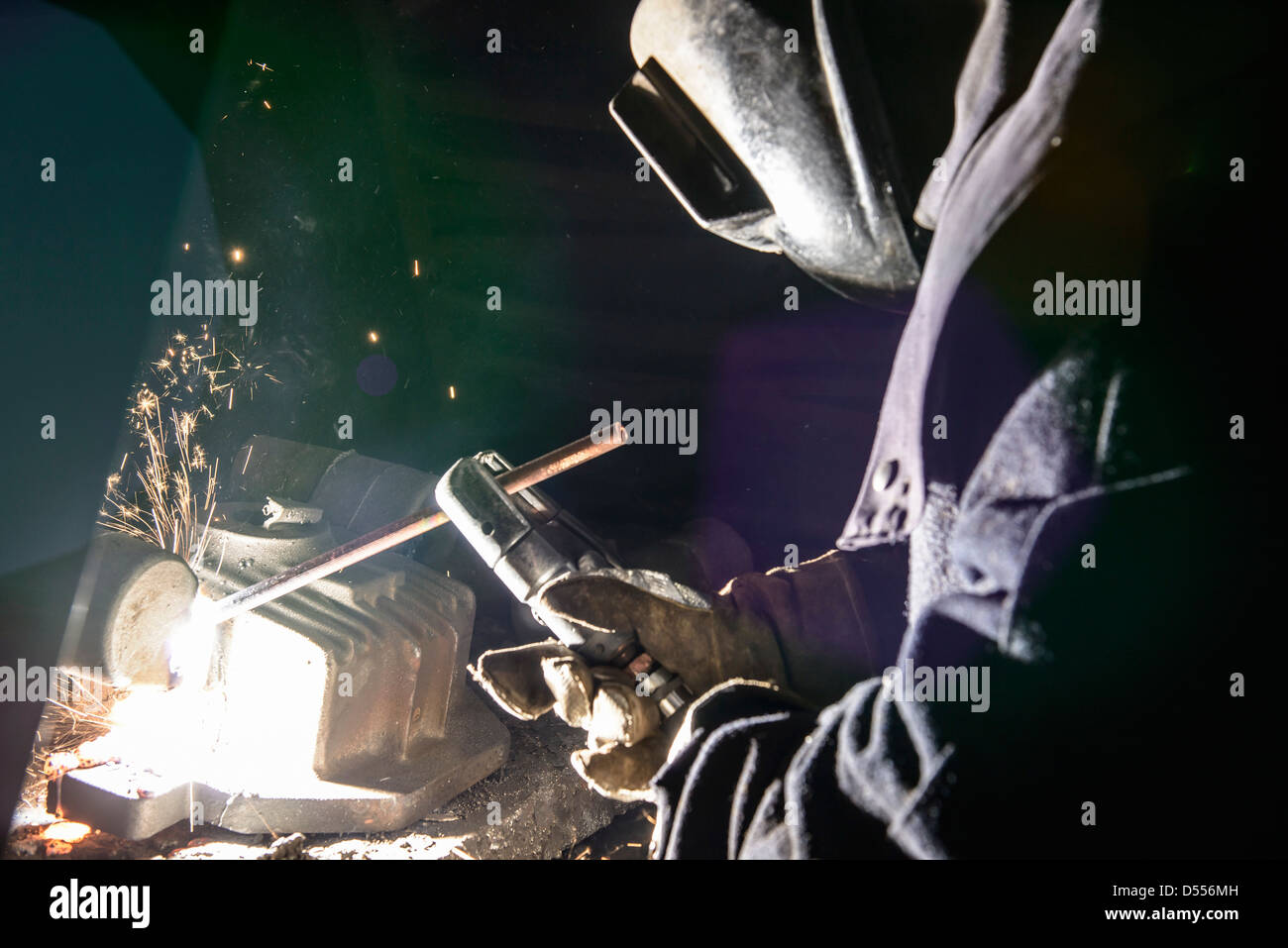 Worker welding metal in foundry Stock Photo