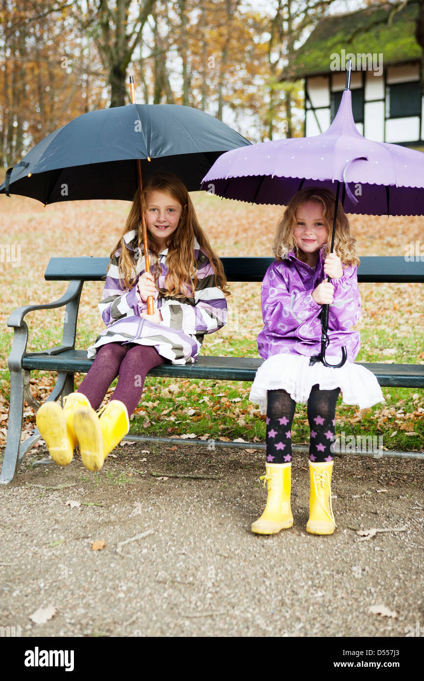 Girls in rain boots and umbrellas in park Stock Photo Alamy
