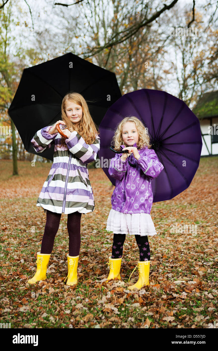 Girls in rain boots and umbrellas in park Stock Photo Alamy