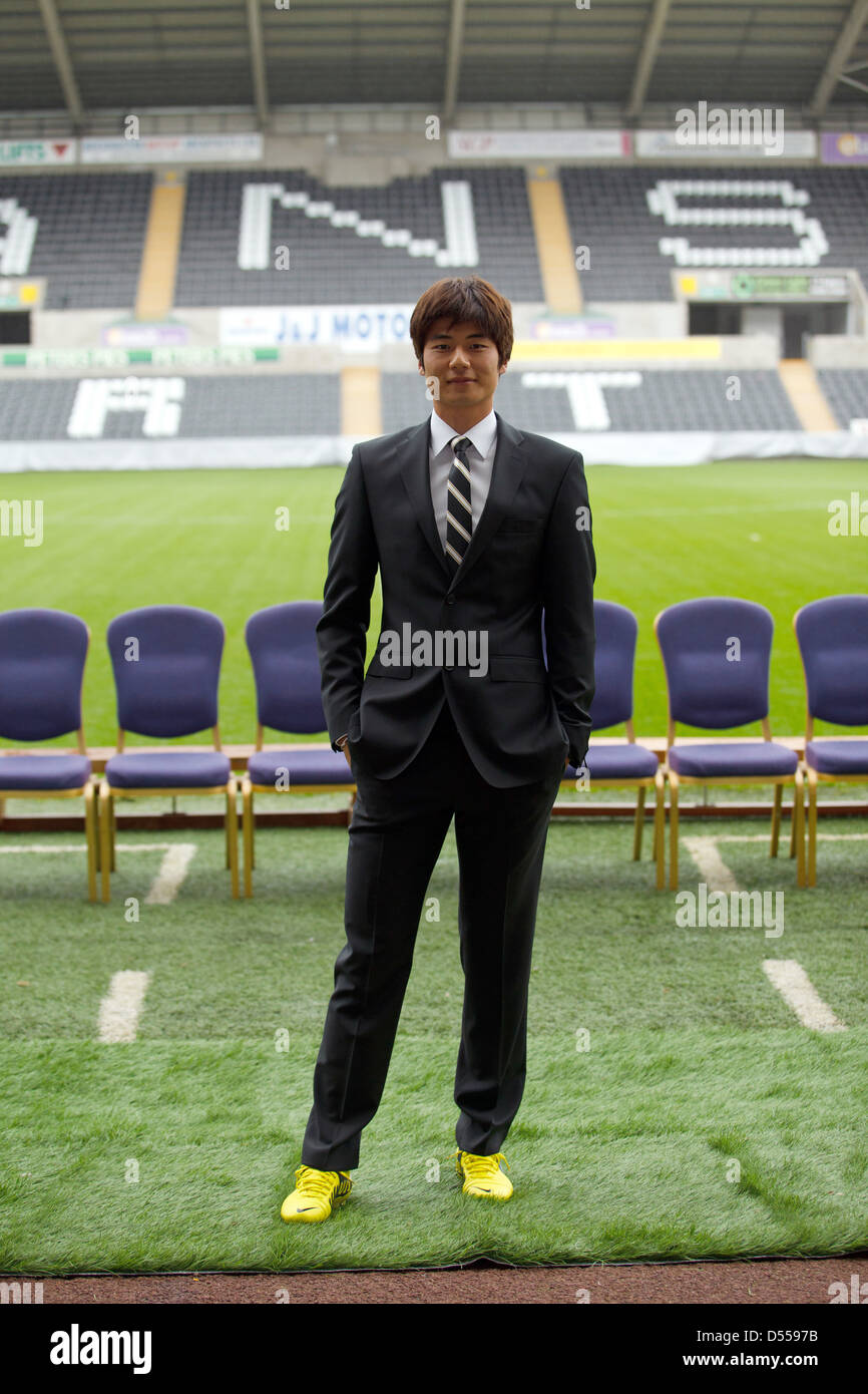 South Korean footballer Ki Sung-Yeung photographed wearing a suit and football boots on the pitch at Swansea's stadium. Stock Photo