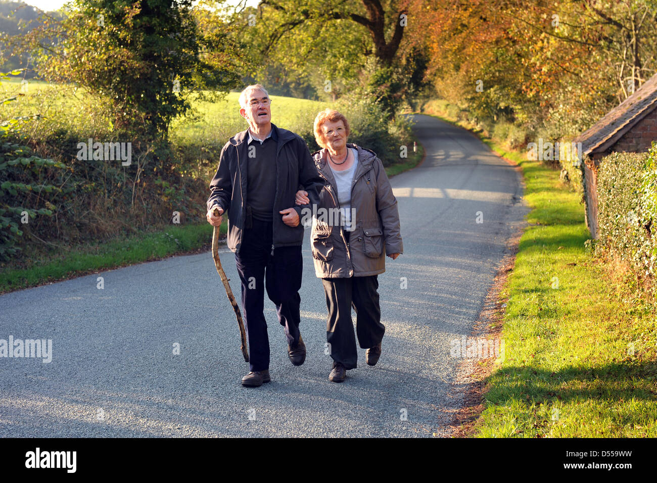 Retired couple enjoy a country walk along a country lane in the Autumn.UK Fully Model released Consented Stock Photo
