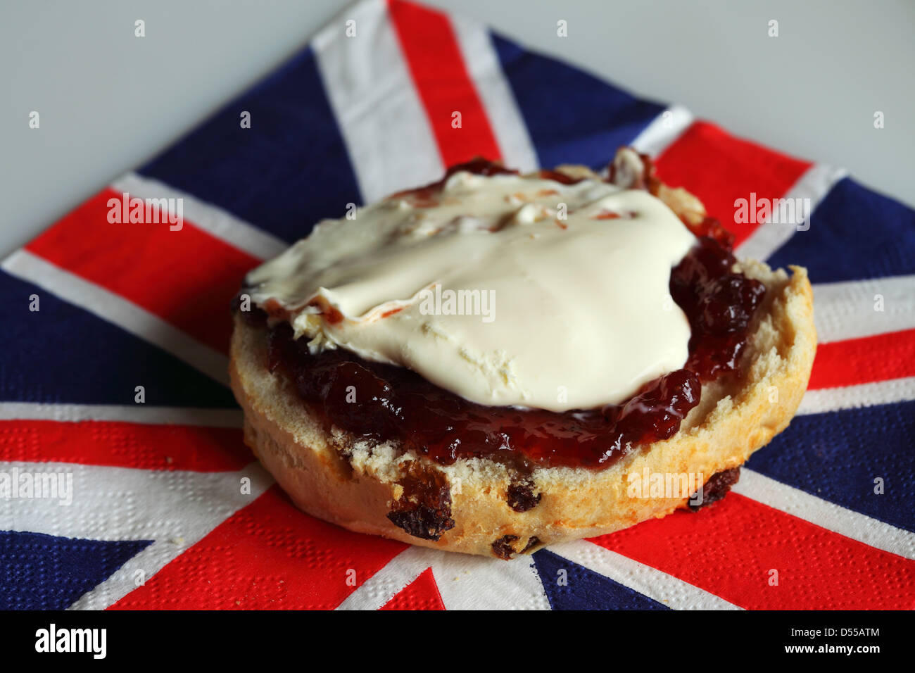 A freshly baked fruit scone with strawberry jam and clotted cream. Stock Photo