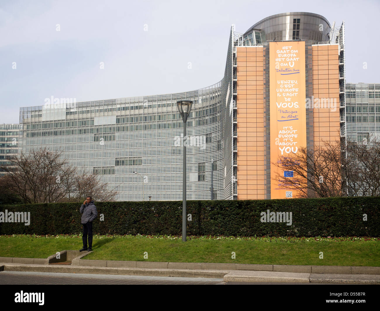 Man using cellphone at Schuman roundabout with the Berlaymont European Commission building in the background. Brussels, Belgium Stock Photo