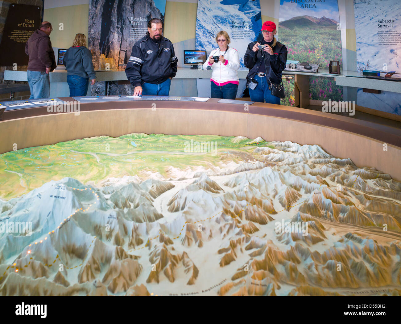 Park visitors view a three dimensional topographical map on display, Eielson Visitor Center, Denali National Park, Alaska, USA Stock Photo