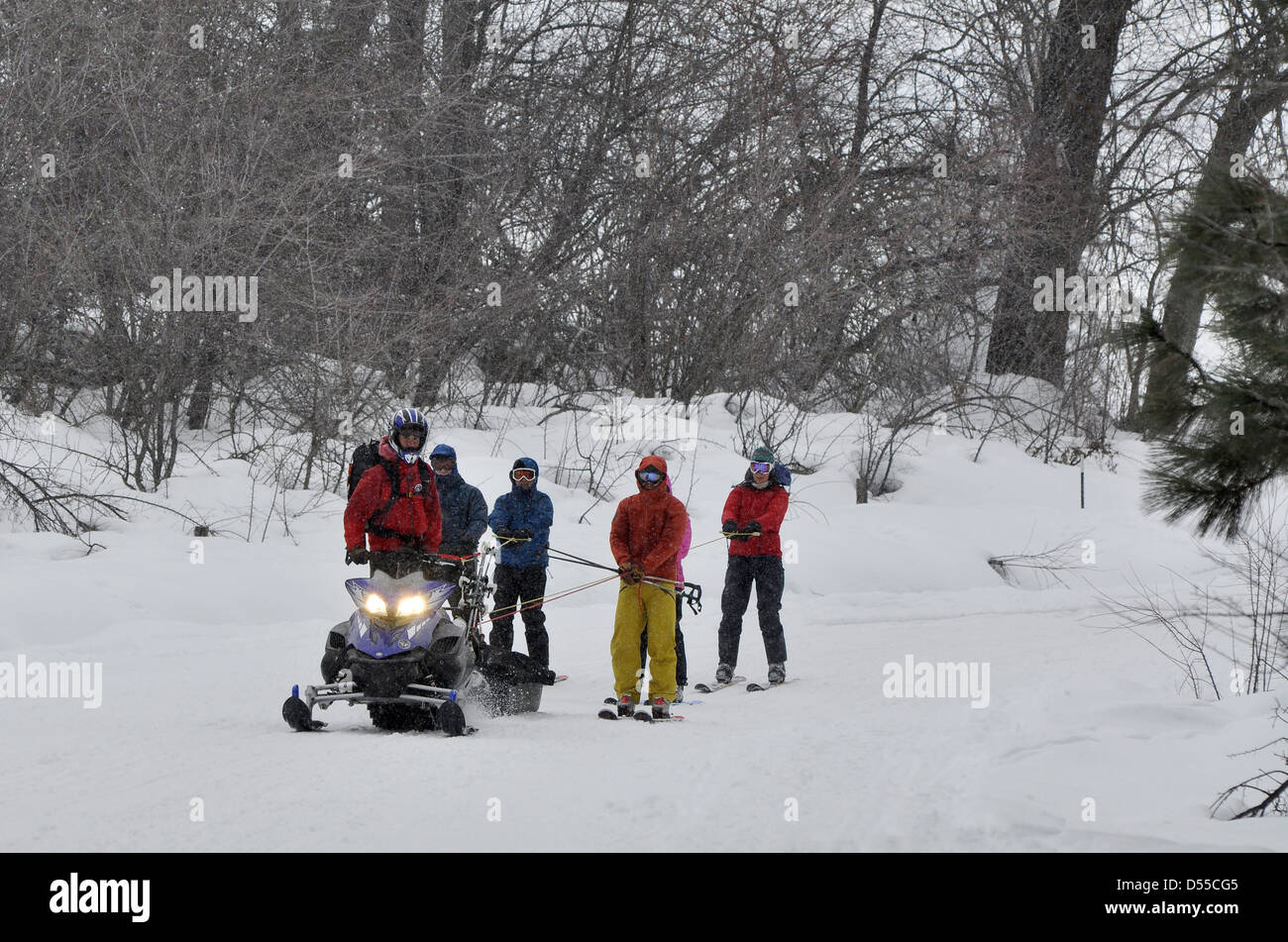 Skiers being towed by a snowmobile,. Wallowa Mountains, Oregon. Stock Photo