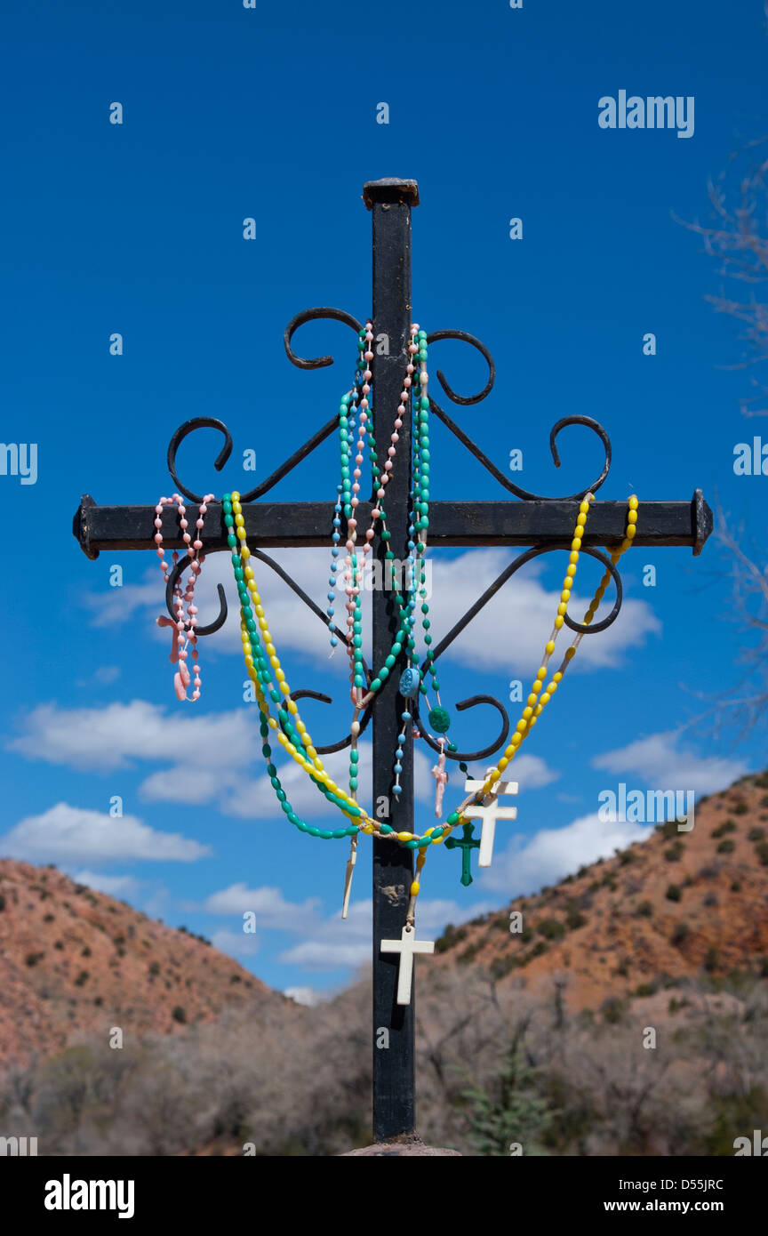 One cross at the Stations of the Cross outside of Santuario de Chimayo Church, Chimayo, New Mexico is covered in rosaries. Stock Photo