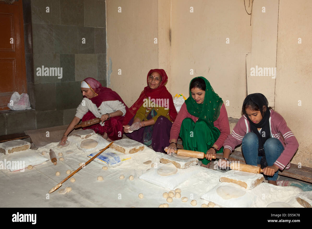 Four women making chapattis in the kitchens of  the Golden Temple complex at Amritsar Punjab India Stock Photo