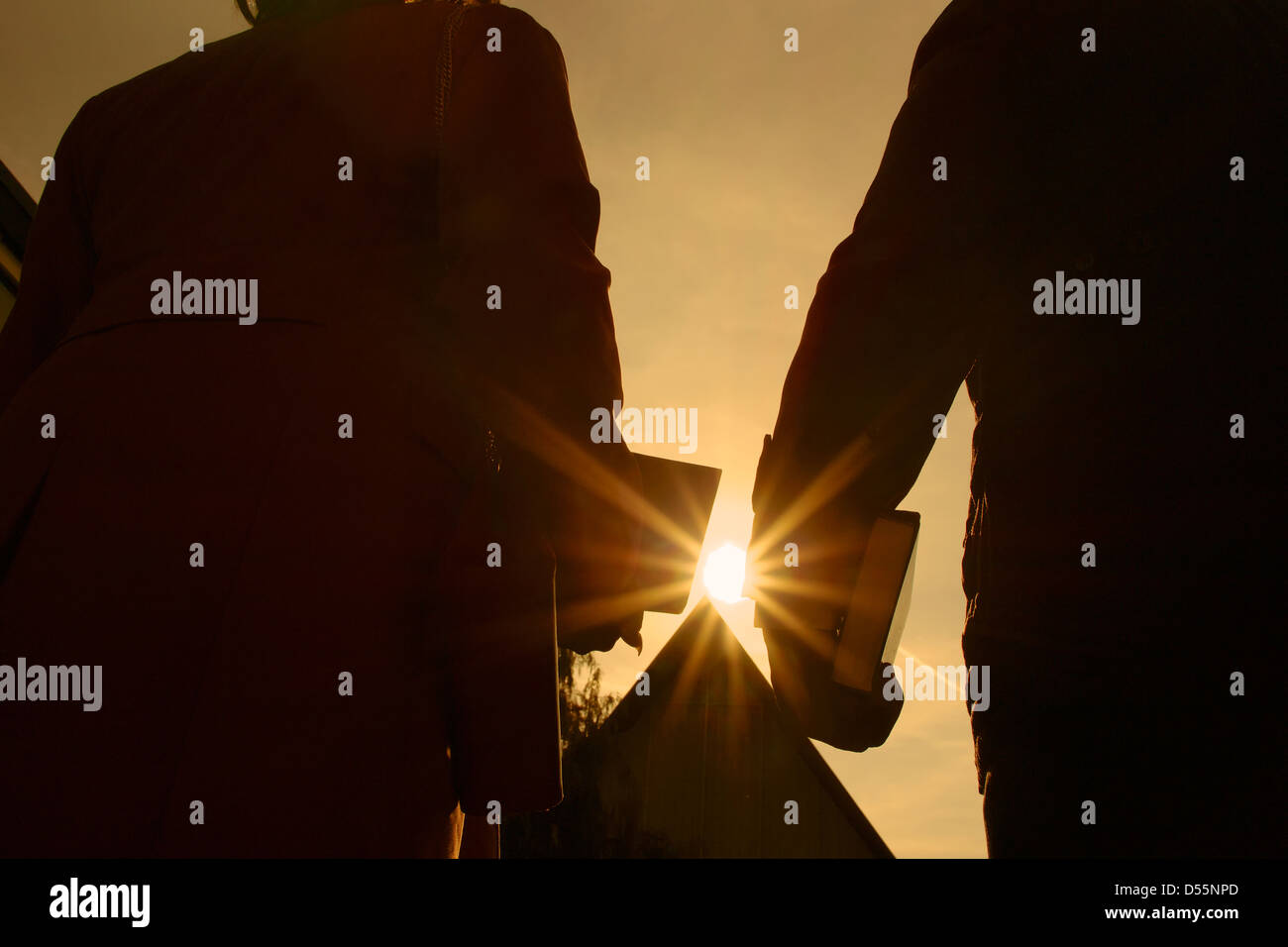 Couple arriving to church with Bibles in their hands as the sun sets. Stock Photo