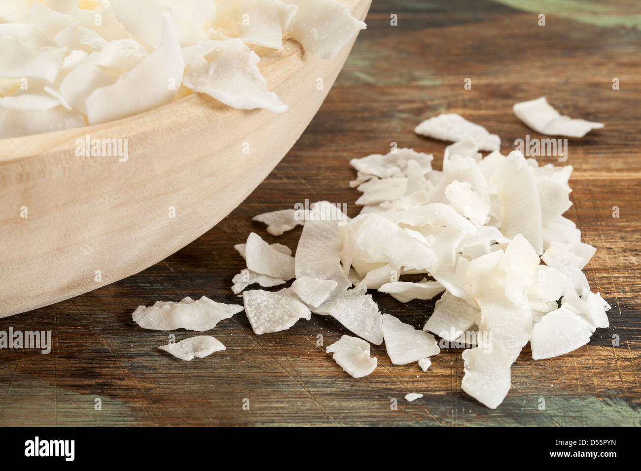 flakes of shredded coconut on a rustic wooden table and in a bowl Stock Photo