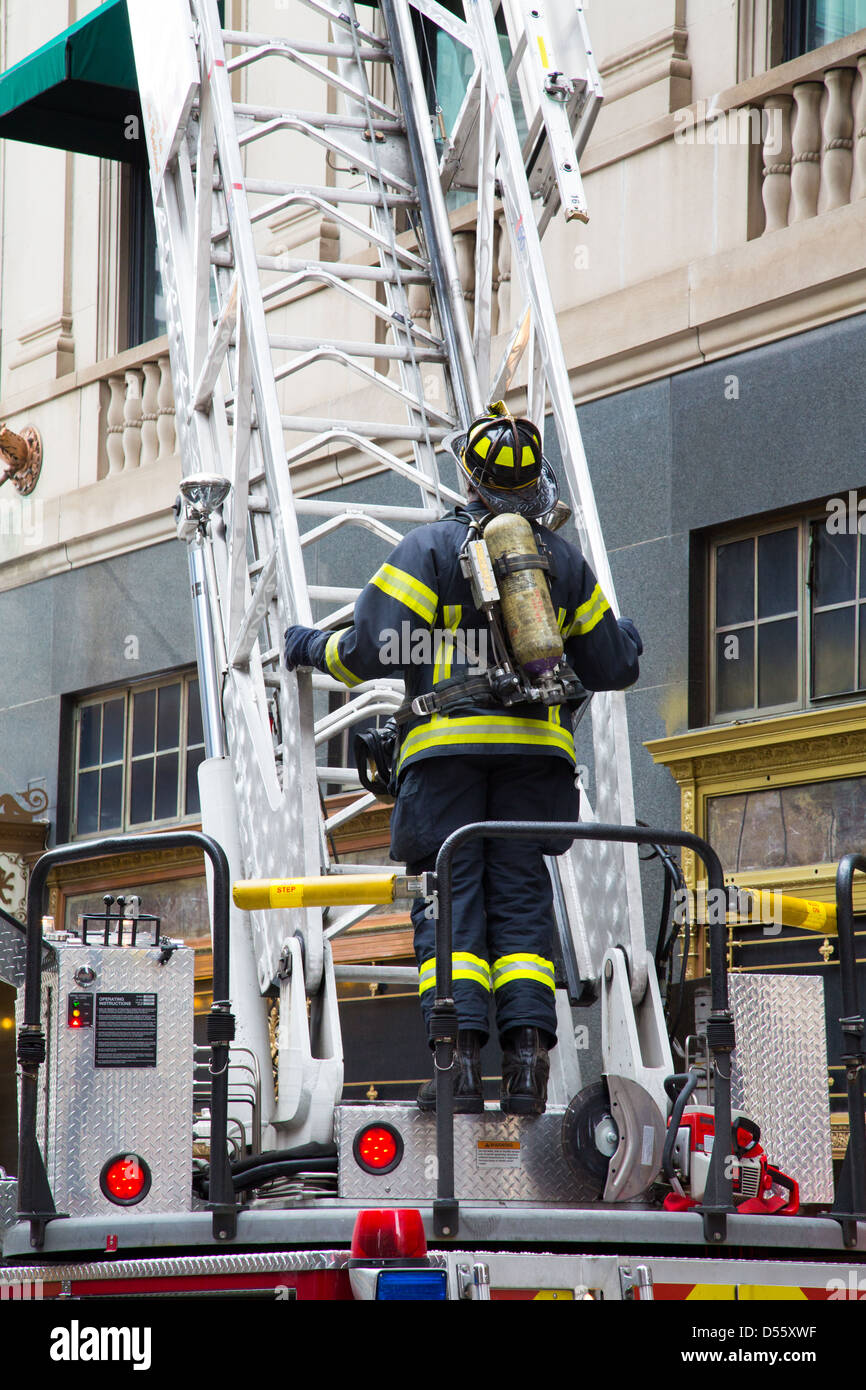 A fireman stands ready to climb the latter on the back of a firetruck at a hotel fire alarm in Boston, Massachusetts Stock Photo