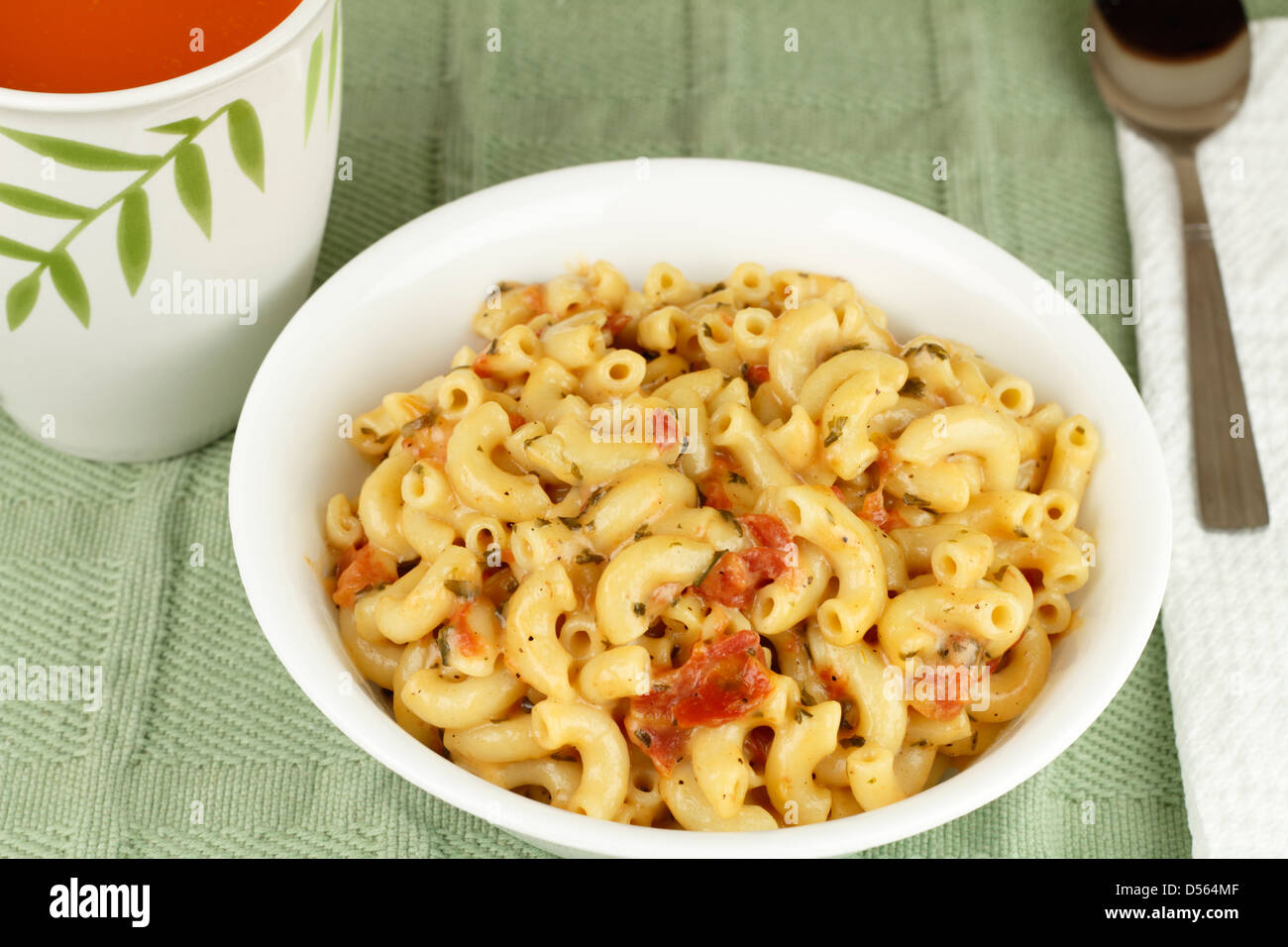 White bowl of a elbow macaroni mixed with melted parmesan cheese, diced