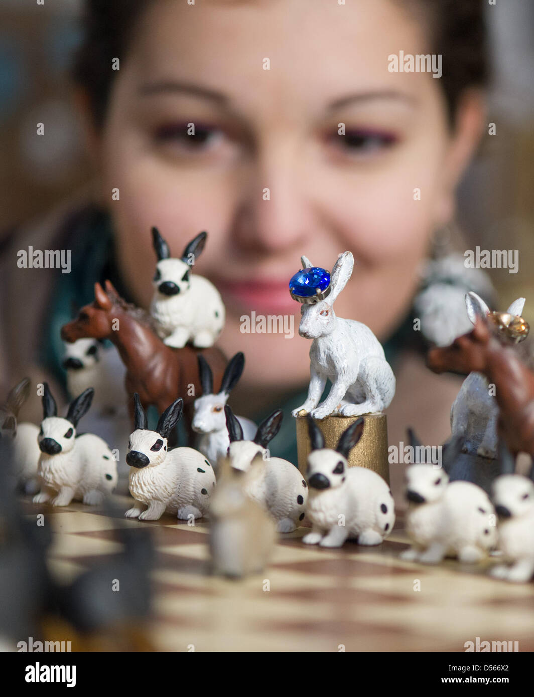 A woman looks at a chess game with figurines of bunnies and horses at