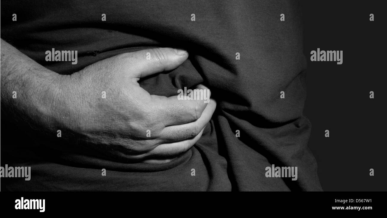 Man holding his stomach with his hands - sick and painful Stock Photo