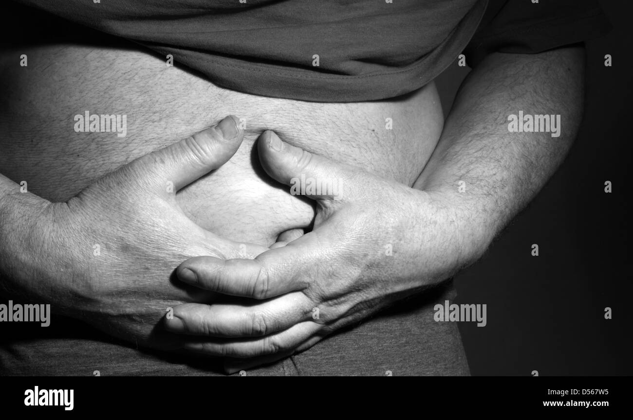 Man holding his stomach with his hands - sick and painful Stock Photo
