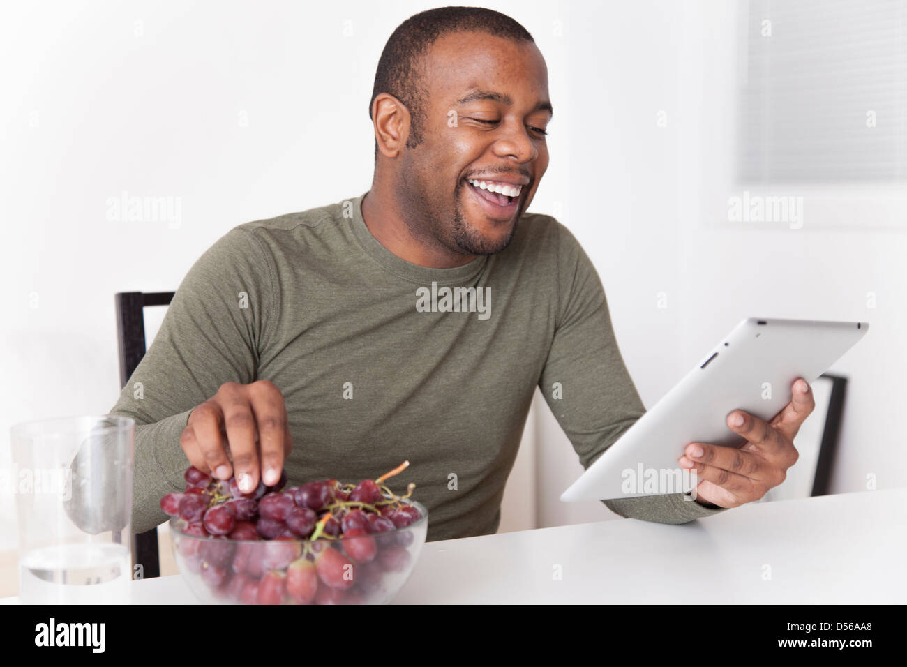black-man-eating-grapes-and-using-digital-tablet-D56AA8.jpg