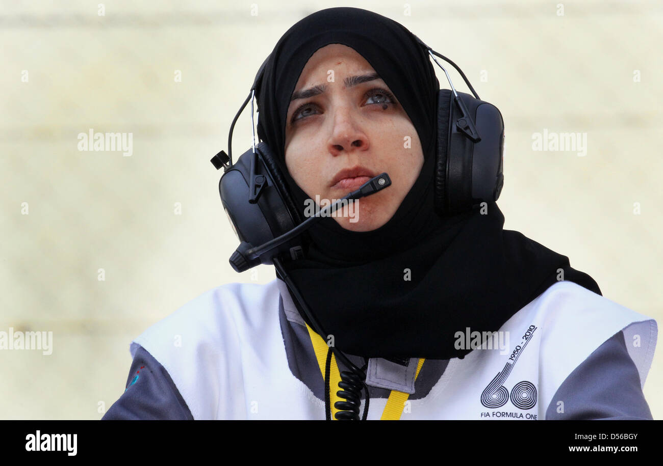 A female motorsport marshal in a headscarf and headphones looks up