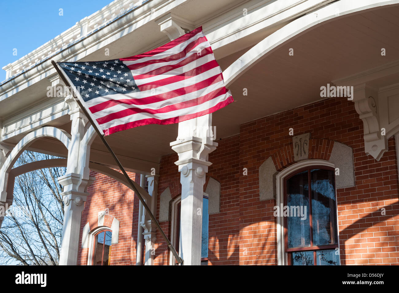 American flag waving from the porch posts of the Historic Walton County Courthouse on the square in downtown Monroe, Georgia. Stock Photo