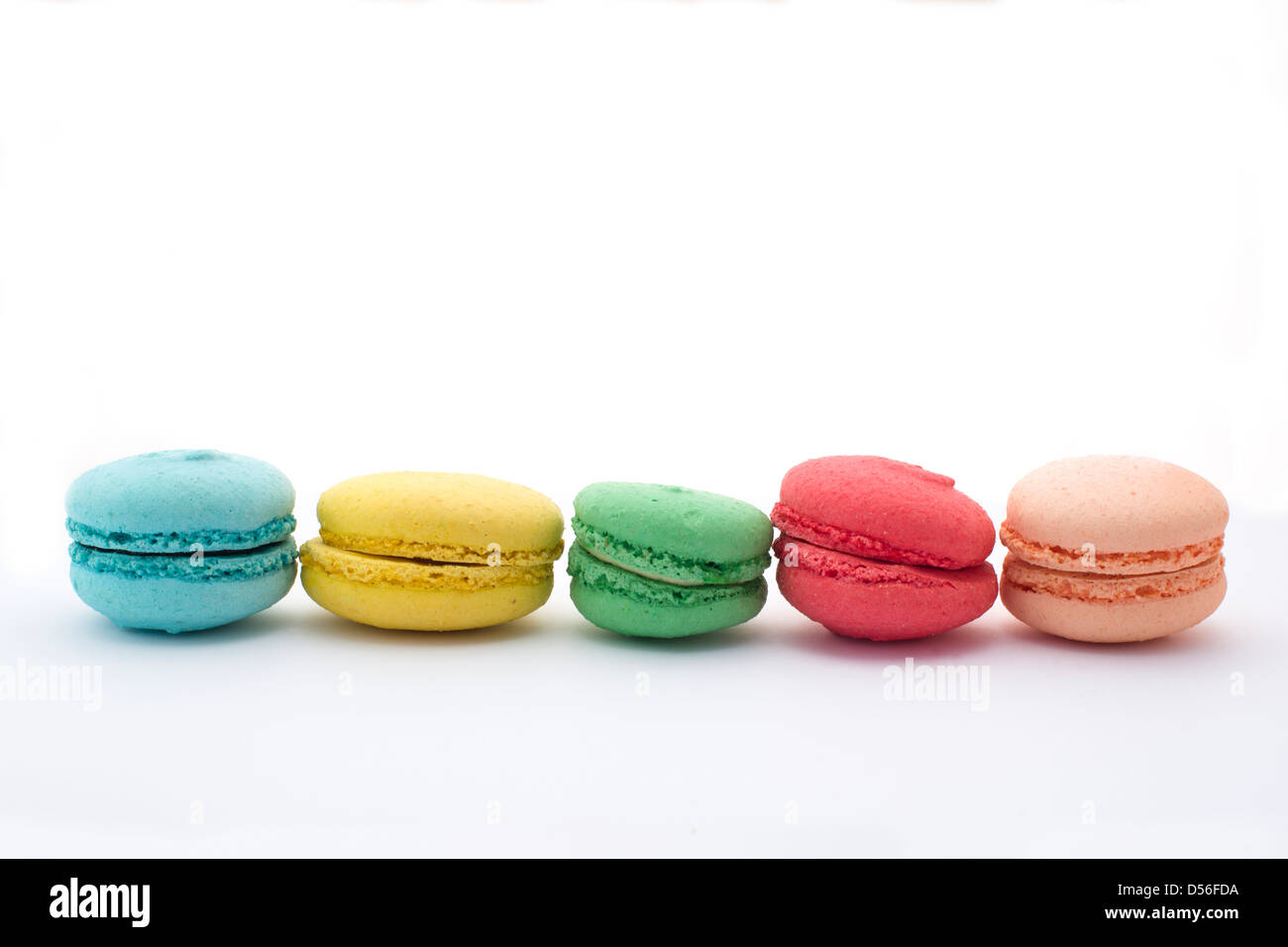 French Macaron cookies in blue, yellow, green, pink and peach on white background. Stock Photo