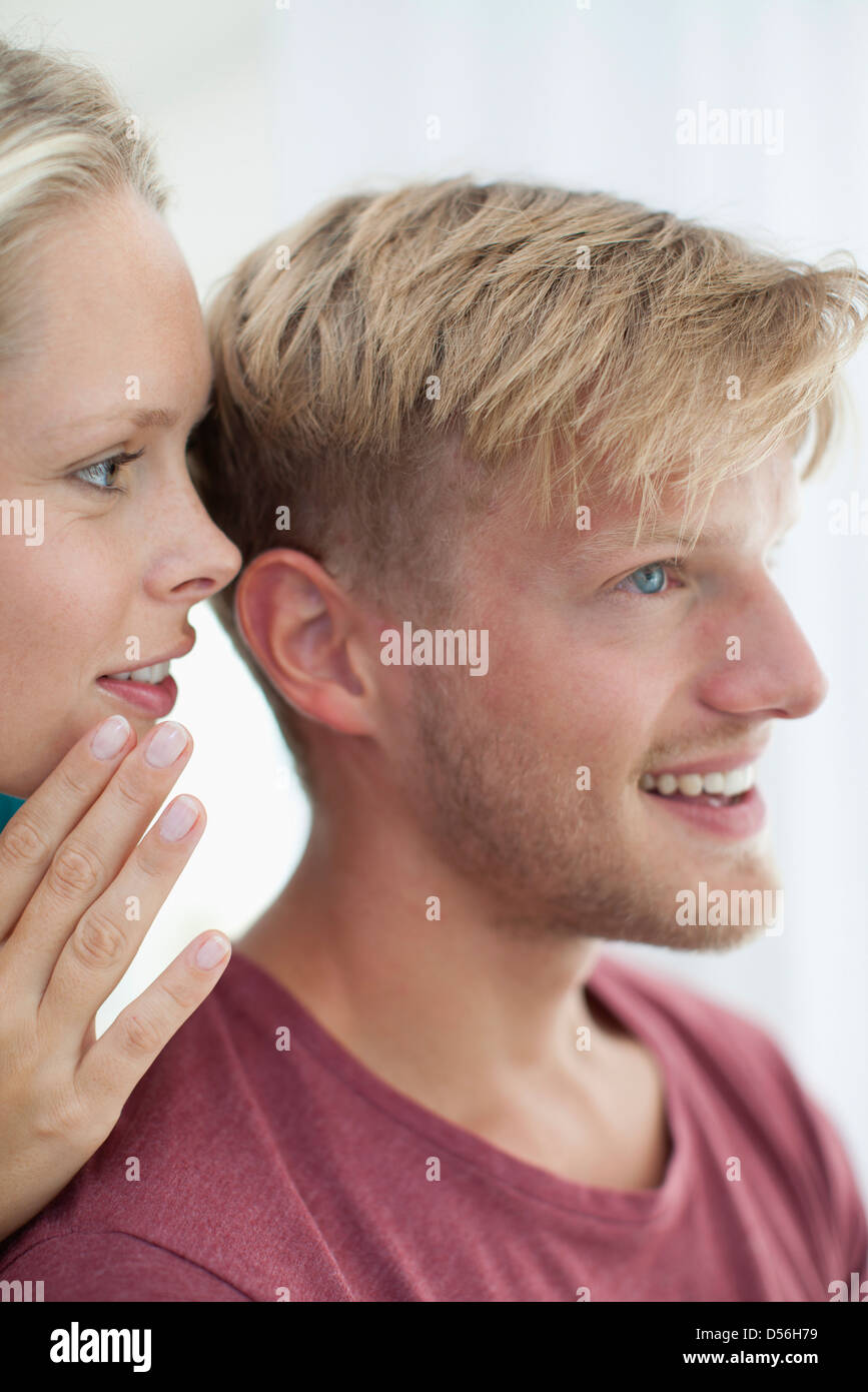 Woman whispering in man's ear Stock Photo