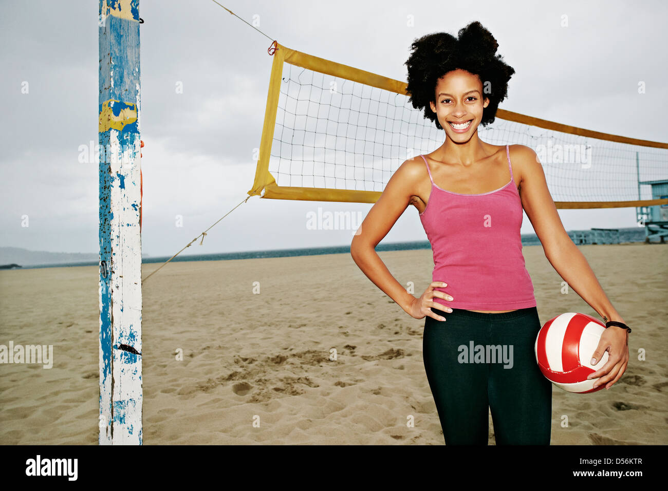 Mixed race woman holding volleyball on beach Stock Photo Alamy