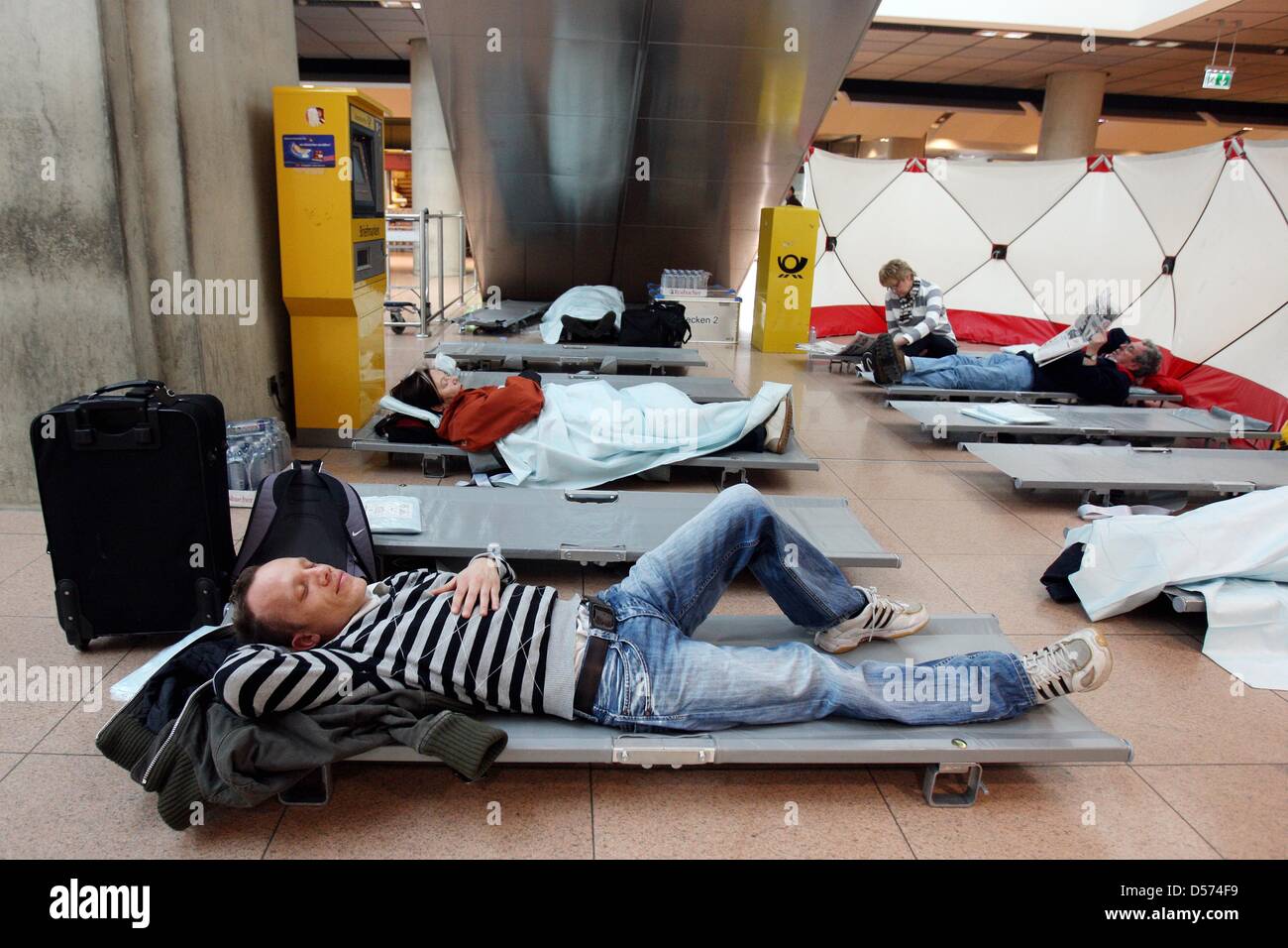 Nikolai Kšrner liegt auf einem Feldbett im Check-In Terminal am Freitag (16.04.2010) am geschlossenen Flughafen Hamburg, da der Flugverkehr wegen der Aschewolke aus Island bis Vormittags gesperrt worden ist. Der Ausbruch des islŠndischen Eyjafjalla-Vulkans hat den Flugverkehr in weiten Teilen Europas lahmgelegt. Foto: Malte Christians dpa/lno Stock Photo