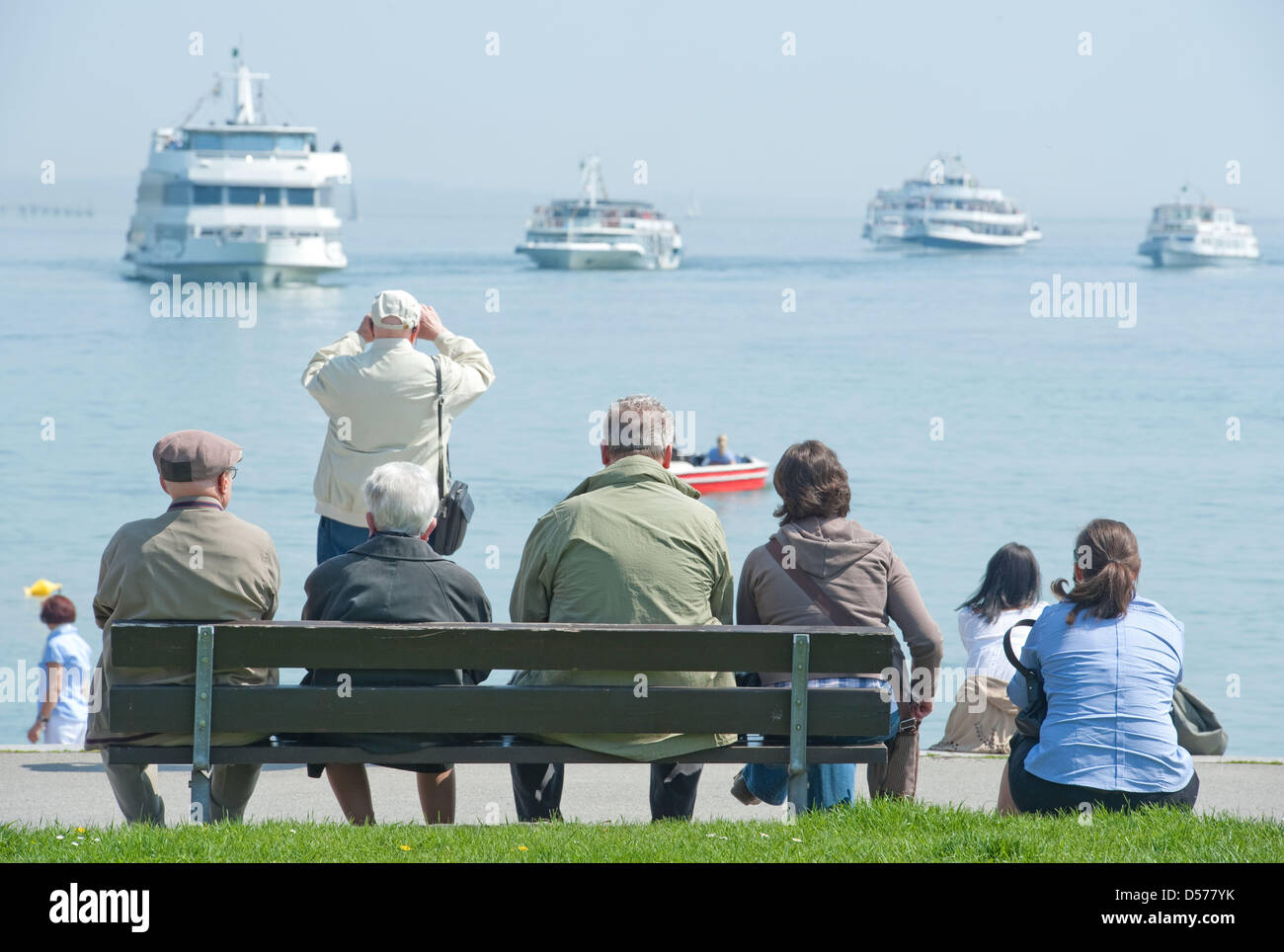 Tourists gaze at Swiss, Austrian and German ships forming a star on Lake Constance near Konstanz, Germany, 24 April 2010. The traditional 'Sternfahrt' ('star cruise') of the 'White Fleet' is the start of season on Lake Constance. It is one of the main attractions in the border triangle. In 2009, 3.9 million passengers cruised over Lake Constance with excursion-boats and ferries. Ph Stock Photo