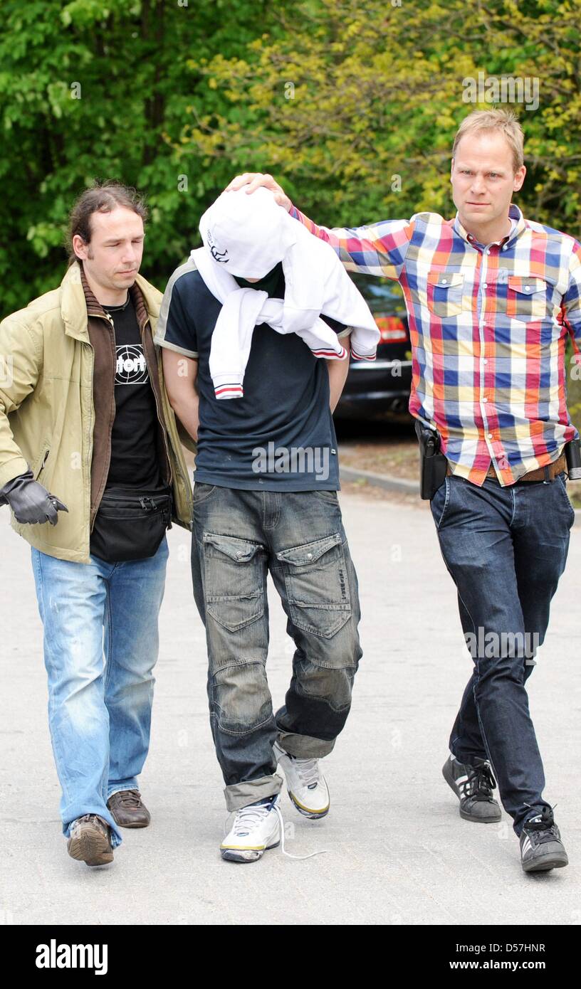 Two plain clothes policemen lead away a suspect in the case of a deadly knife stabbing in Hamburg, Germany, 17 May 2010. A 19-year-old man was stabbed to death in a central Hamburg subway station on 14 May 2010. The police has arrested four young men in connection with the crime. One of them has previously been convicted for assault and battery. Photo: MAURIZIO GAMBARINI Stock Photo